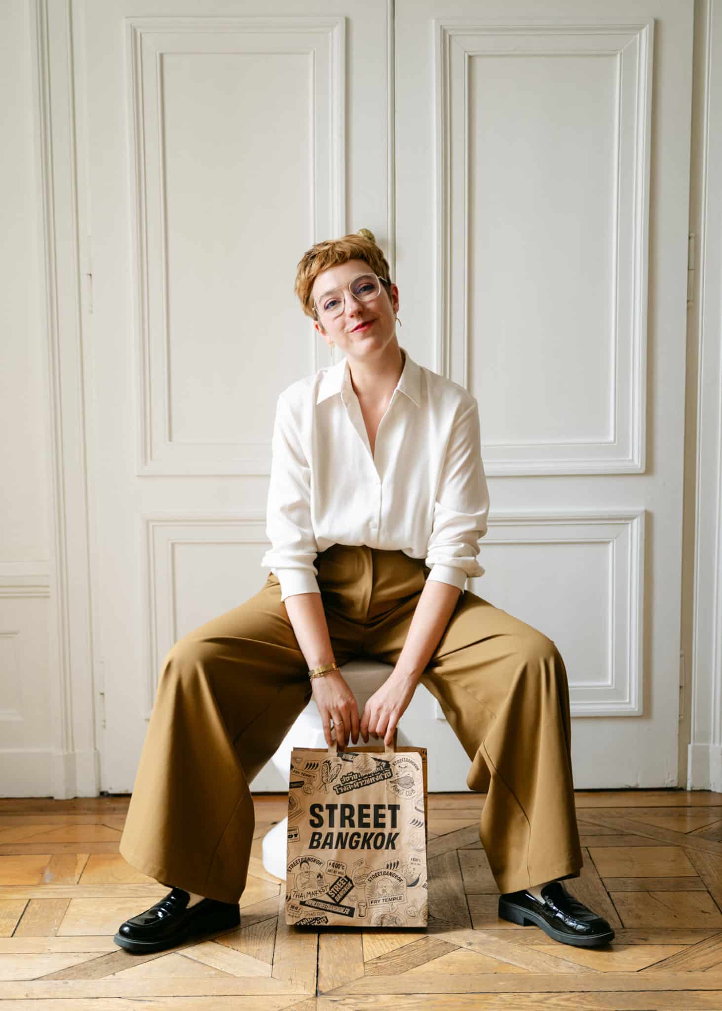 portrait décontracté d'une directrice artistique spécialisée du secteur food, avec dans les mains le sac de take-away de la chaine de restaurant Street Bangkok